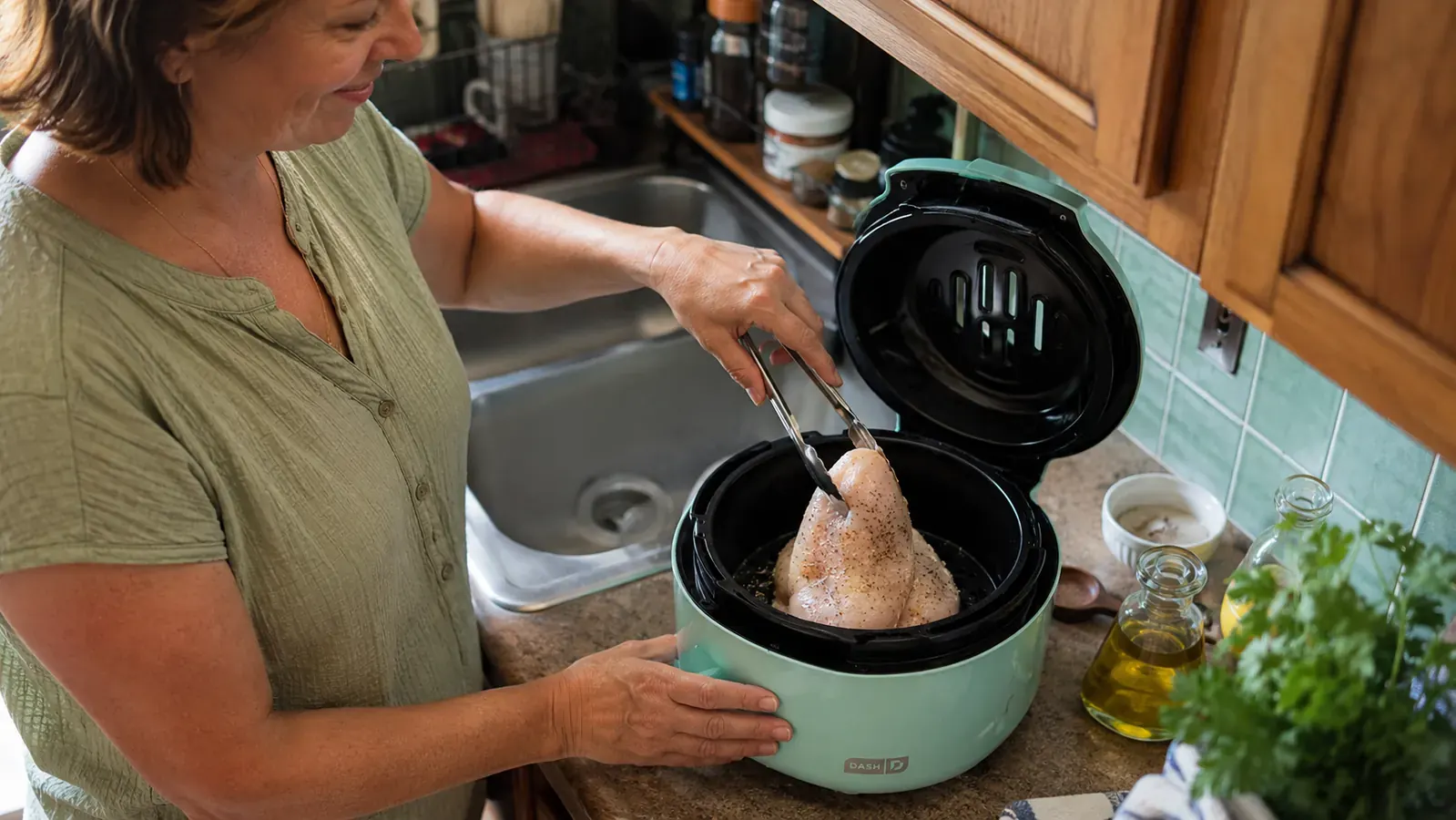 Hand checking a chicken breast that doesn't lay flat inside the Dash Tasti-Crisp basket