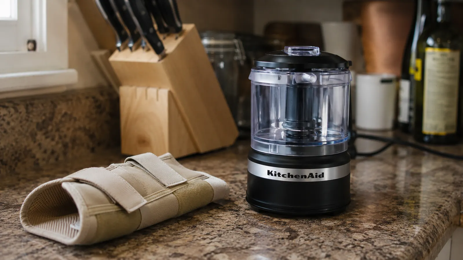 Close view of a wrist brace resting on a kitchen counter next to the small electric chopper