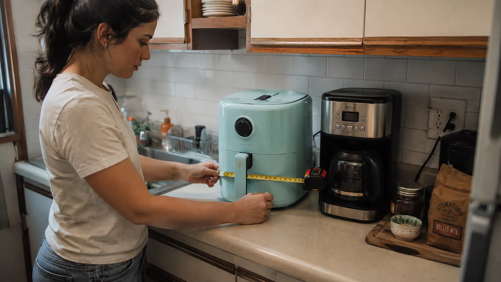 Small kitchen counter with the air fryer tucked next to a coffee maker, basket-width shown against a ruler