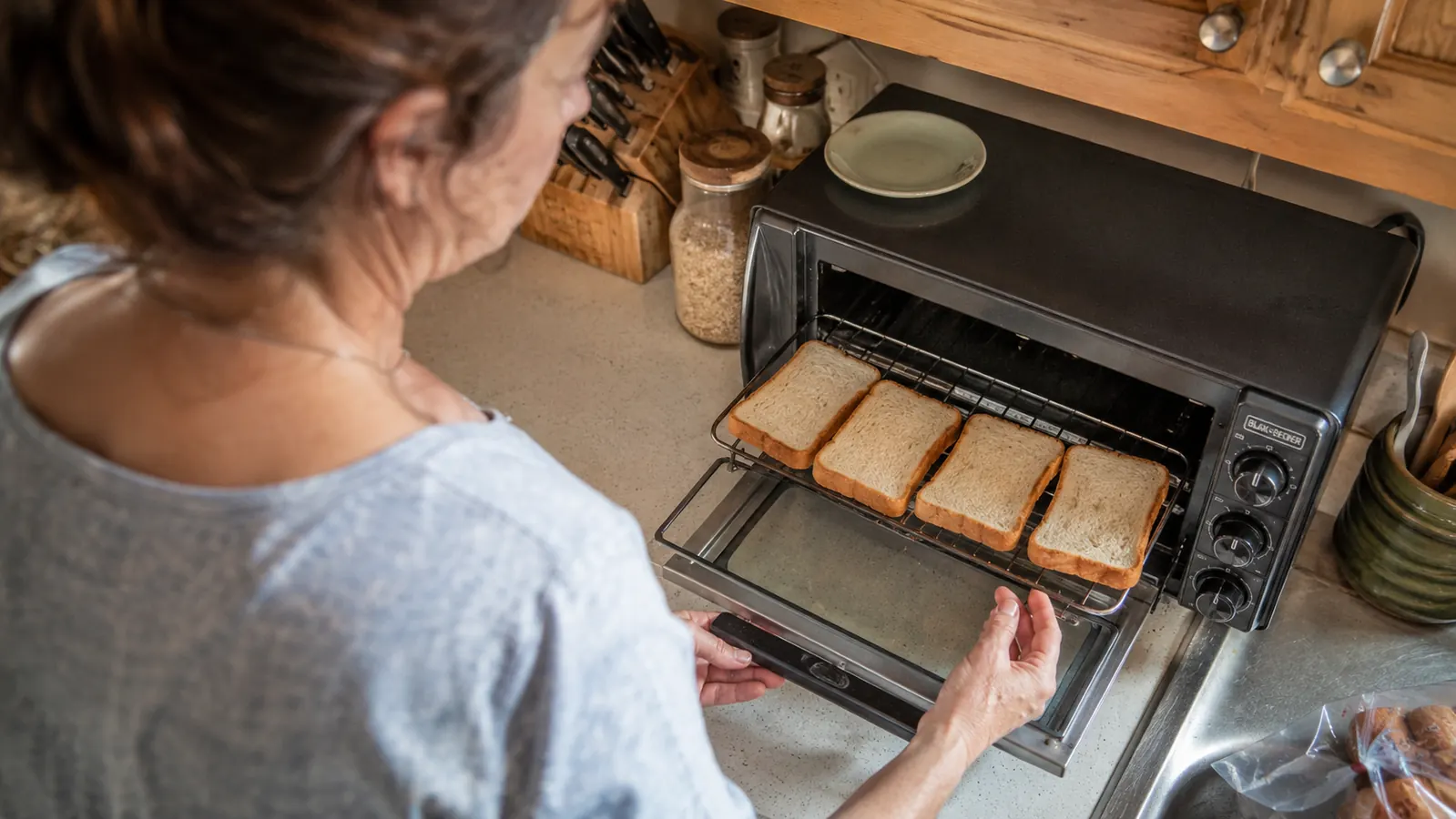 Overhead view of four slices of bread arranged in the toaster oven rack with two slices angled toward the center