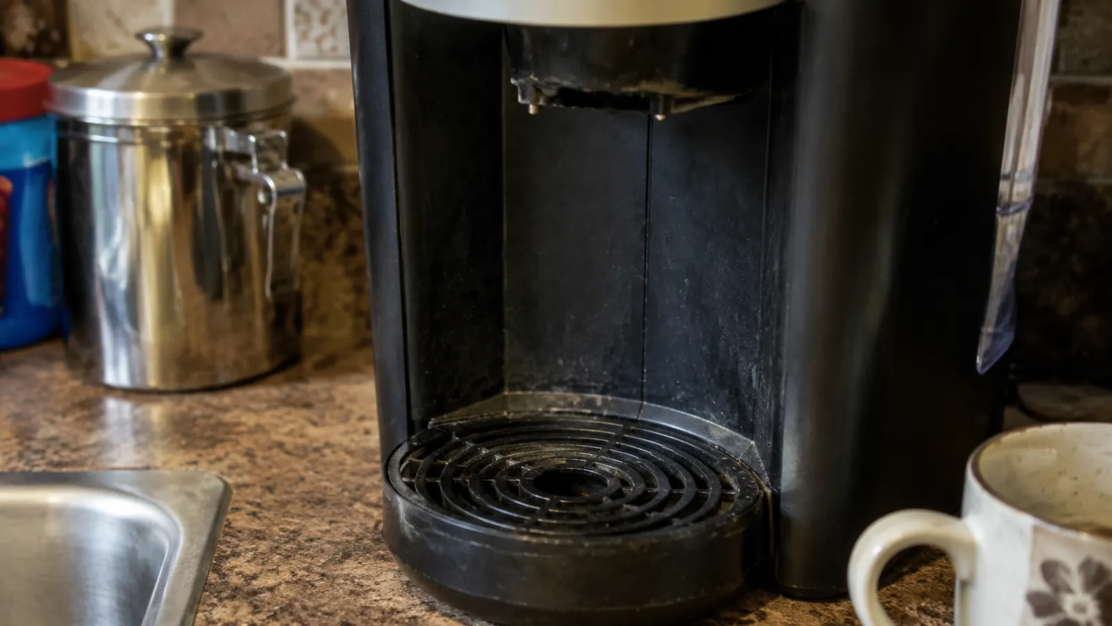 Close-up of a Keurig K-Express drip tray with faint water spots and mineral staining after months of daily use