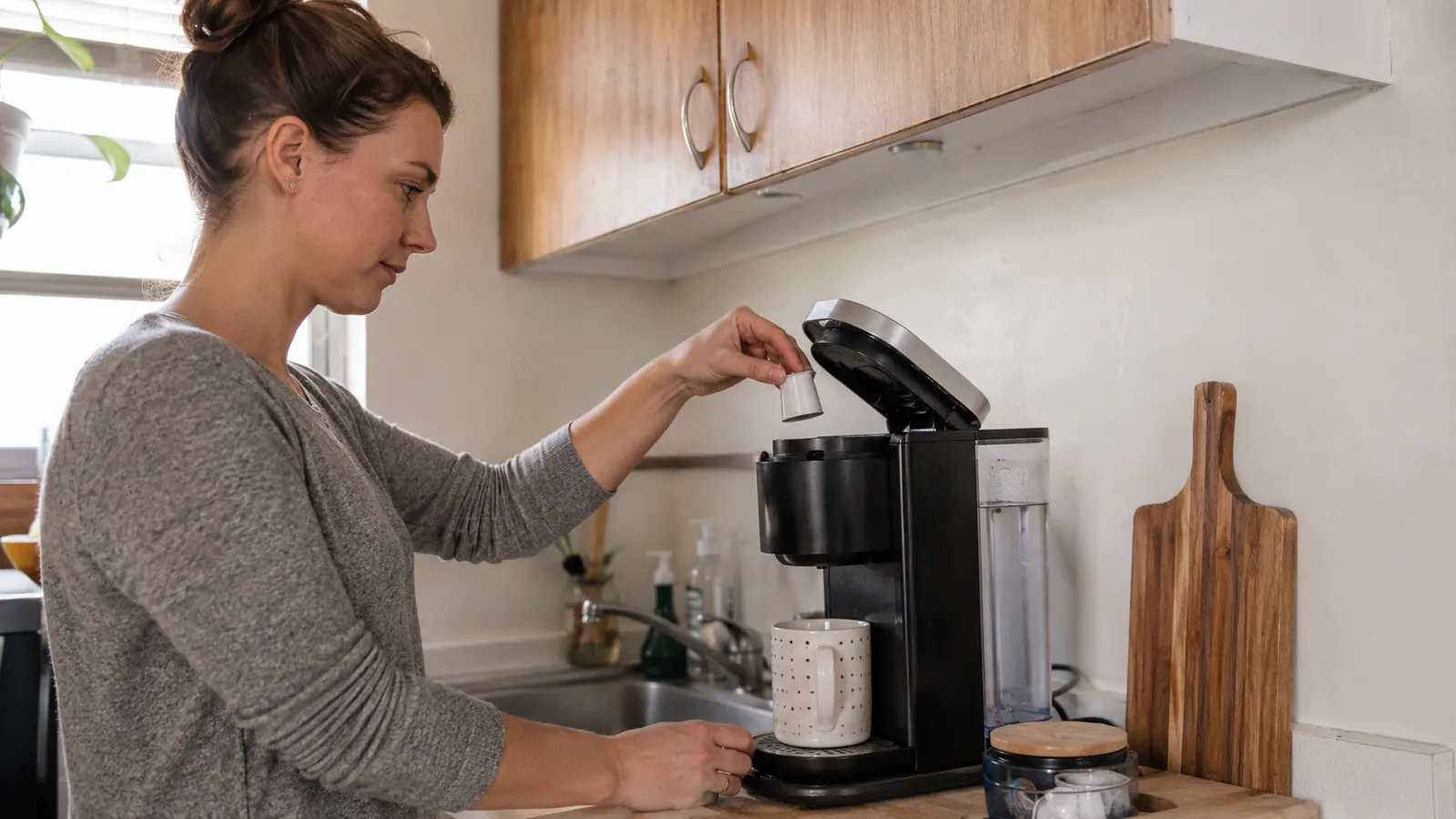Coffee maker lid lifted open for a K-Cup pod with an upper cabinet just above it, showing tight but workable clearance